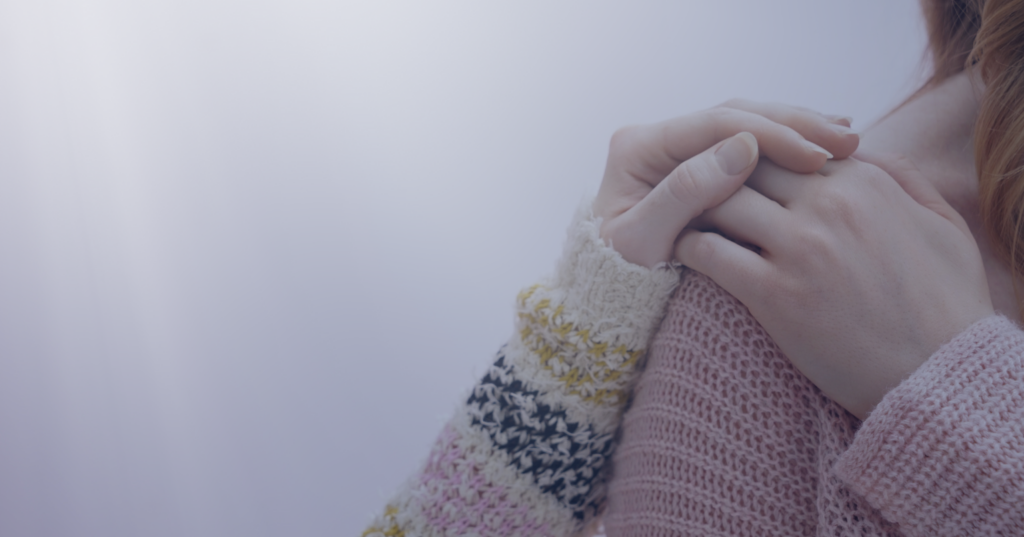 Close-up of a person holding their own hand, symbolizing self-care and emotional support.